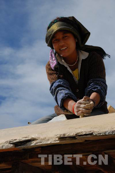 A Tibetan girl tamps the Aga clay at Pingcuolin Monastery in Shigtse Prefecture, Tibet Autonomous Region, photo from China Tibet Online.