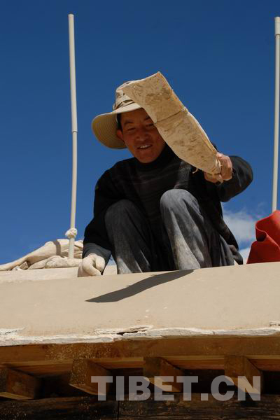 A Tibetan worker hammers the Aga clay with a flat wooden tool at Pingcuolin Monastery in Shigtse Prefecture, Tibet Autonomous Region, photo from China Tibet Online.
