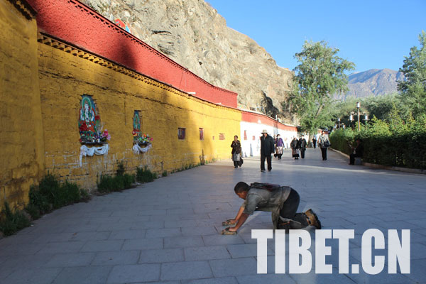 In the morning, a pilgrim kneels down for a full-body prostration towards the Potala Palace. [Photo/Tibet.cn]