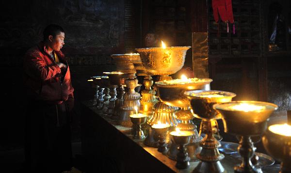 A monk stands in front of butter lamps in the Kejia Monastery in Burang County of Ngari Prefecture, southwest China's Tibet Autonomous Region. The Kejia Monastery, close to Nepal and India, is a famous Monastery of Sakya Sect of Tibetan Buddhism. The senior monk Lotsawa Rinchen Sangpo directed the building of the Monastery in 996. The construction of the Monastery is magnificent with a lot of big and small halls for scriptures and marvelous frescos. In 2001, the Kejia Monastery was appraised as the state-level important protection unit of cultural relic. Some 15 million yuan (2.3 million US dollars) were invested to restore the two big halls of the Monastery and the protection work will soon be carried out to mend the frescos. [Photo/Xinhua]